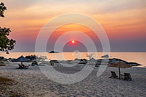 Idyllic beach with tables and sun loungers at sunrise photo