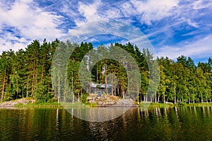 Idyllic countryside landscape view with blue lake and house on the shore. Summer cottage in Finland.