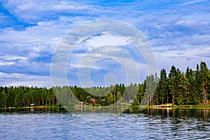 Idyllic countryside landscape view with blue lake and house on the shore. Summer cottage in Finland.