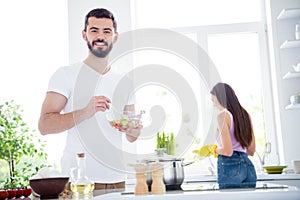 Idyllic family portrait concept. two people stay home kitchen man mix salad spoon bowl his wife wash plate in yellow