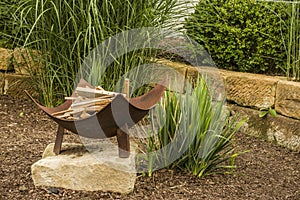 Idyllic fireplace with metal fire bowl in the garden with ornamental grass