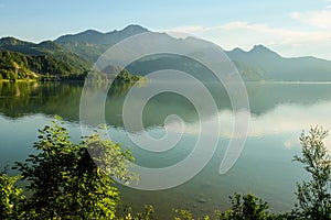 Idyllic foggy mountain landscape with a lake and mountains in the background