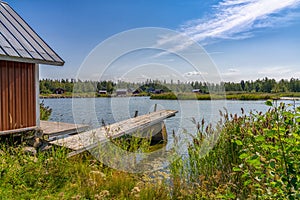 Idyllic lake landscape with a wooden cottage and a wooden dock on a beautiful summer day