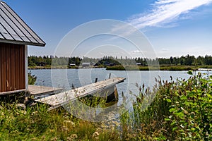 Idyllic lake landscape with a wooden cottage and a wooden dock on a beautiful summer day