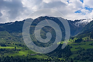 Idyllic landscape in the Alps in springtime with traditional mountain chalet and fresh green mountain pastures with flowers.