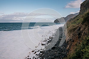 Idyllic landscape featuring a rocky shoreline and a large cliff, with the rolling waves of the ocean