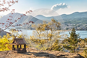 Idyllic landscape in the Japan with traditional wooden toy house and beautiful lake with mountains at the background