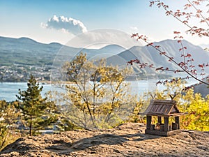 Idyllic landscape in the Japan with traditional wooden toy house and beautiful lake with mountains at the background