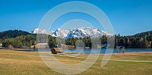 Idyllic landscape lake geroldsee with wooden hut and walkway, view to karwendel mountains in spring