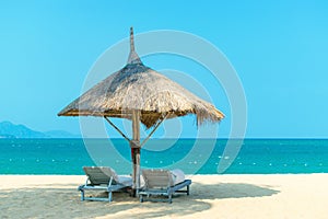 Idyllic landscape paradise scene at beach with strawy loungers on clear blue sky photo