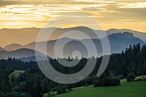 Idyllic landscape in the Pieniny Mountains with trees and fresh green meadows and foggy hills in the background