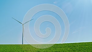 An idyllic picture of pure energy - a wind generator on a green hill in the rays of the sun