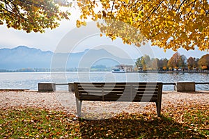 Idyllic place at lakeside Mondsee with bench and view to shipping pier Gmunden, autumn austria
