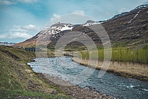 Idyllic river at Seydisfjordur, Iceland, with mountain range in the background, wide angle shot