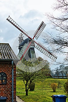 Idyllic rural landscape featuring a traditional windmill in the background, with lush trees