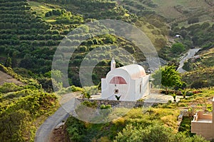 Idyllic rural landscape with hills covered by olive trees and tiny peaceful orthodox church in beautiful sunset light, Crete,