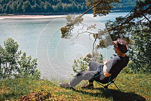 idyllic and rural scene. A man chilling and resting after hiking sitting on a folding chair and looking at the distance in the