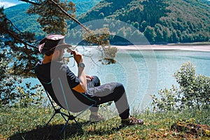 idyllic and rural scene. A man chilling and resting after hiking sitting on a folding chair and looking at the distance in the