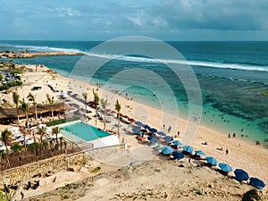 Idyllic scene of Pantai Melasti beach on a bright and sunny day, brimming with people and umbrellas