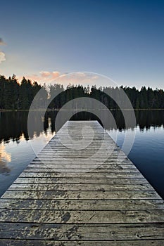 Idyllic scene of a wooden dock extending out onto a serene lake at sunset