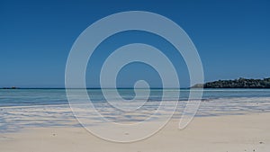 Idyllic seascape. Calm turquoise ocean, white sandy beach, clear azure sky.