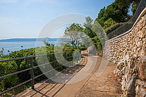 Idyllic seaside promenade with fence, along Moscenicka Draga coastlilne, with view to Losinj island, croatia photo