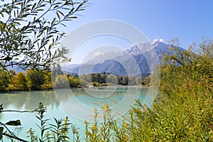 Idyllic shore landscape with pebble beach, blue water, flowers and mountains