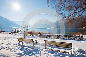 idyllic snowy scenery at spa garden Schliersee with two benches and lake view, bavaria