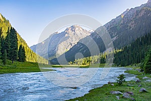 Idyllic summer landscape with hiking trail in the mountains with river with reflection and forest.