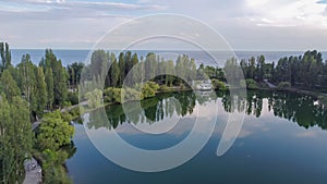 Idyllic summer landscape with pond with reflection and trees near Issyk kul lake, Kyrgyzstan.