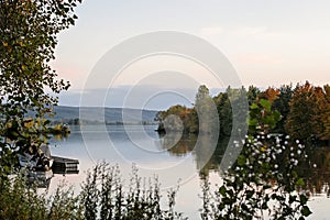 Idyllic sunset over lake in autumn. Sunset boat on lake. Colorful trees reflection in the water. Lake Slnava, Piestany, Slovakia.