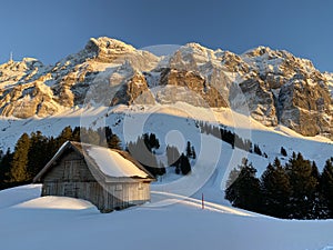 Idyllic Swiss alpine mountain huts dressed in winter clothes and in a fresh snow cover on slopes on the Alpstein mountain range