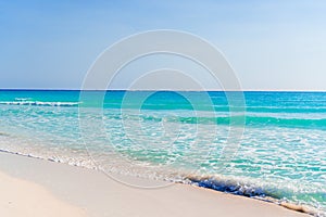 Idyllic tropical beach with white sand, turquoise ocean water and blue sky on Caribbean island