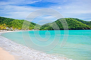 Idyllic tropical Carlisle bay beach with white sand, turquoise ocean water and blue sky at Antigua island