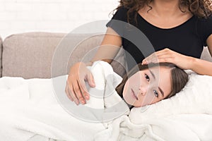 Sad girl lying on mother`s knees on sofa