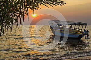 Idyllic view on boat floating on waves against of sunset