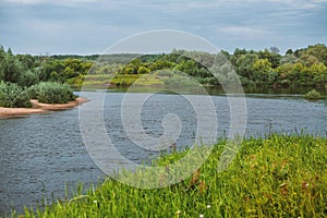 View of a calm, rural scene with a wide river reflecting the peaceful, verdant greenery of the countryside photo