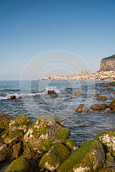 Idyllic view of Cefalu from the long sandy beach. Cathedral and Rocca di Cefalu rocky mountain on a sunny day in Cefalu, Sicily,