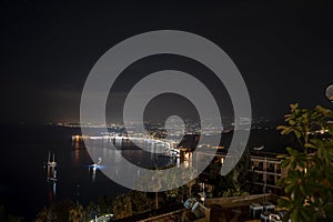 Idyllic view of Hotel Elios and Mount Etna at illuminated coast by sea in night photo