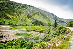 Idyllic view in Glendalough Valley, County Wicklow, Ireland. Mountains, lake and tourists walking paths