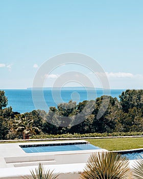 Idyllic view of the ocean and a luxurious swimming pool surrounded by lush green trees