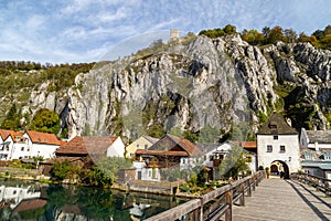 Idyllic view at the village Essing in Bavaria, Germany with the Altmuehl river, high rocks in background and a wooden bridge in