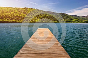 Idyllic view of the wooden pier in the lake with mountain scenery background. Wooden bridge on the lake. Wooden pier jutting out