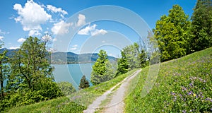 Idyllic walkway at Leeberg hill, view to lake Tegernsee, blue sky with clouds. spring landscape