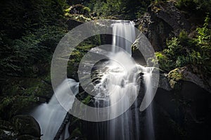 Idyllic waterfall falls into a dark gorge.