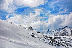 Idyllic winter landscape with hiking trail in the mountains. Rocks, snow and stones in mountain valley view. Mountain panorama.