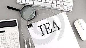 IEA written on paper with office tools and keyboard on the grey background