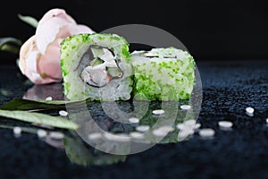 Ð iece of sushi with caviar. Green land. Green caviar. Sushi on the glossy surface of the table