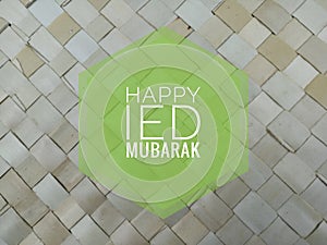 Ied mubarak. Happy Ied Mubarak card on blurry background of  natural palm leaf mat.