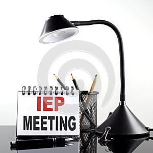 IEP MEETING text on notebook with pen and table lamp on the black background